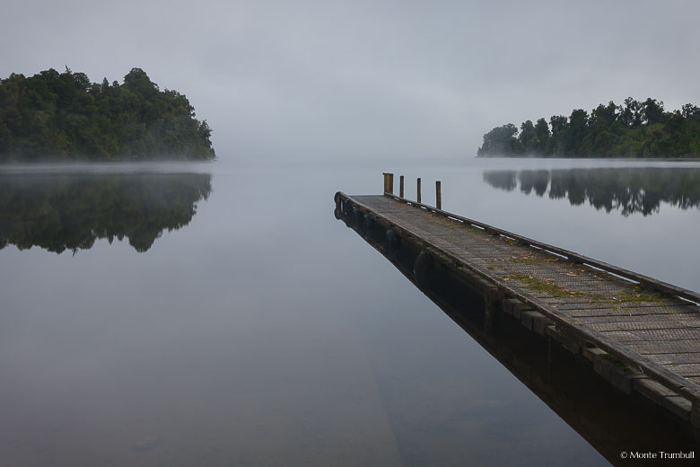 Early morning fog lifts off of Lake Mapourika on the South Island of New Zealand.