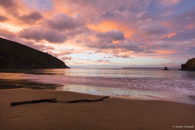 Rain clouds break up and take on glorious pastel shades at dawn at Whites Bay in New Zealand.