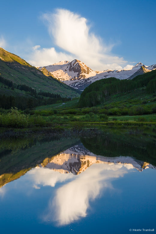 A towering cloud rises above Augusta and Purple Mountains and is reflected in a beaver pond outside of Crested Butte, Colorado.