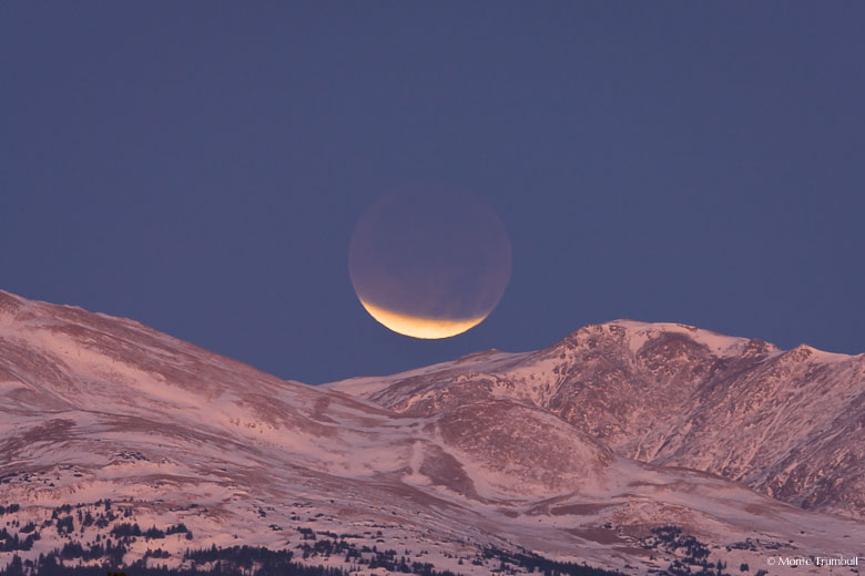 During a lunar eclipse, a sliver of the full moon remains exposed as it sets over the Rocky Mountains outside of Buena Vista, Colorado.