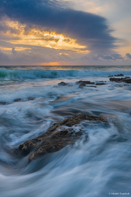 Waves crash into a rocky beach at sunrise in Coral Cove State Park, Florida.