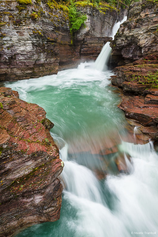 The Saint Mary River slices through a narrow rocky crevice and surges down Saint Mary Falls before taking a quick turn and rushing downstream towards Saint Mary Lake in Glacier National Park, Montana.