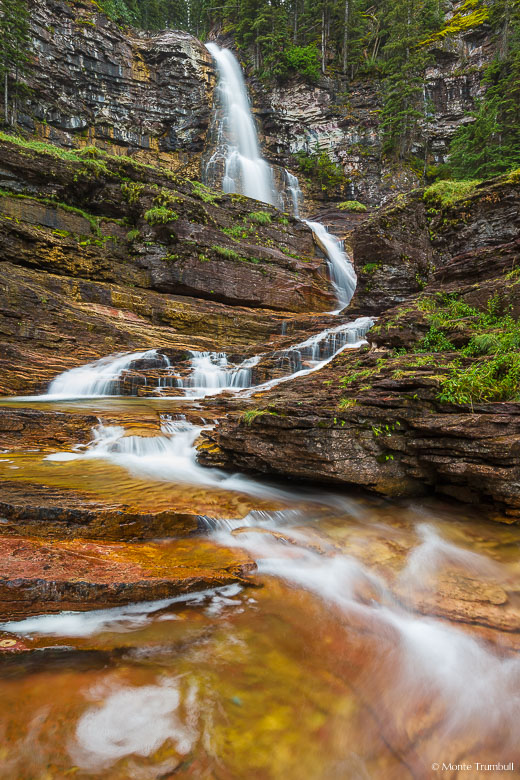 Virginia Falls twists and turns its way down a red rock wall on its journey to meet up with the Saint Mary River in Glacier National Park, Montana.